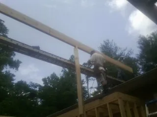 Carpenter setting a ridge beam over a new addition frame — Ice Dam Removal by Roofing Brothers in Newburgh