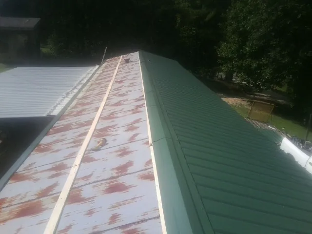 Old rusted panels beside newly installed green metal roofing — Wind Damage Roof Repair by Roofing Brothers in Newburgh