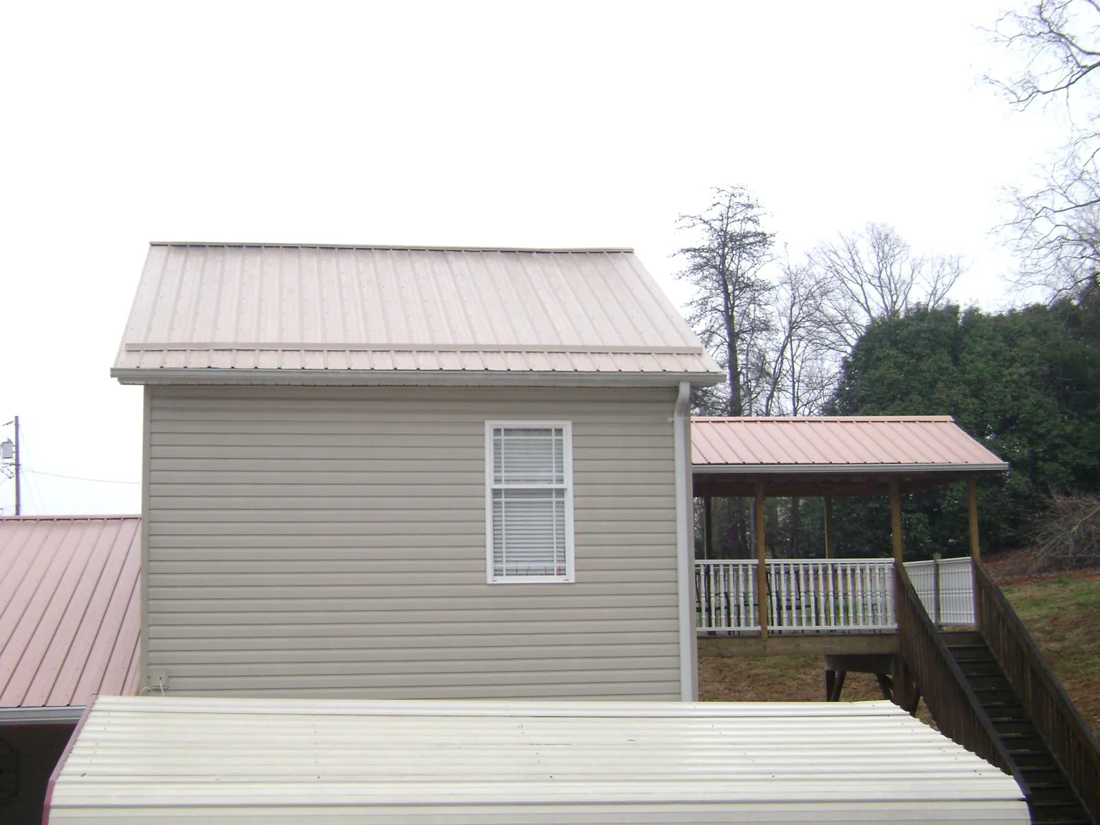 Tan metal roofs on a two story addition and attached porch, from a Roof Replacement job in Newburgh